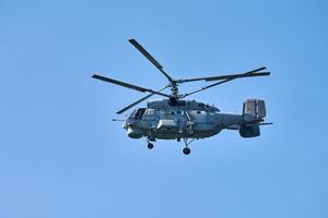 Navy helicopter flying against blue sky background, copy space. One rotary wing aircraft, side view photo