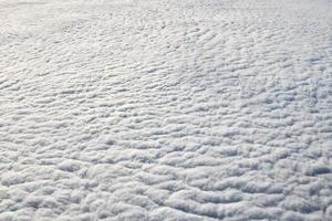 Over clouds top view from aircraft window, thick white blue clouds looks like soft foam photo