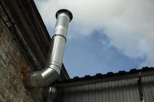 Pipe on garage. Steel pipe in brick wall. Stainless steel. photo