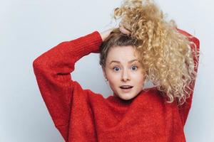 Emotional surprised female strares at camera with unexpected look, keeps hair in pony tail, expresses surprisment, isolated over white studio background. Its unbelievable Amazement and shock photo