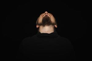 Cute bearded man, threw head back, black background photo