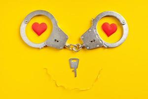 Handcuffs smile shape on yellow background. Freedom concept. photo