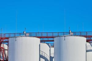 White fuel storage tanks against blue sky background photo