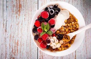 granola, cereales muesli con yogur o leche y bayas frescas. concepto de desayuno saludable. foto