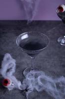 Halloween black cocktail in glasses with candy eyeball. Party festive celebrate concept. photo