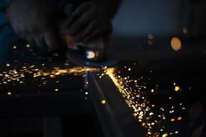 Sparks in dark. Metal grinding. Orange lights fly in different directions. Work in metal workshop. photo