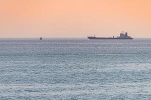 pequeño remolcador y gran carguero. hermosa puesta de sol sobre el mar. impresionante vista de viaje, espacio de copia. foto