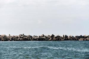 Concrete breakwaters tetrapods, blocks and stones in calm blue sea, horizon. Beautiful seascape photo