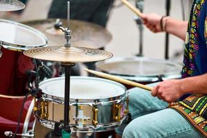 Drummer man playing drums percussion with drum sticks, drum set on concert stage, sticks and drums photo