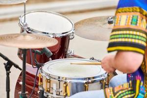 Drummer man playing drums percussion with drum sticks, drum set on concert stage, sticks and drums photo