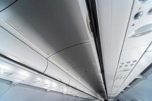 Airplane air conditioning control panel over seats. Stuffy air in aircraft cabin with people. New low-cost airline. photo