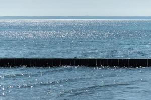 Breakwater on beach. Wooden sea separator. Beautiful seascape. Protection holidaymakers from effects of both weather and longshore drift. photo