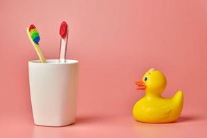 Two toothbrush and duck toy, copy space. Personal care tool for protect oral cavity, remove plaque and tartar. photo