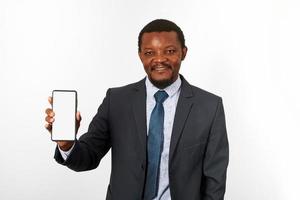 hombre negro afroamericano sonriente en traje de negocios con maqueta de teléfono inteligente en la mano, fondo blanco foto