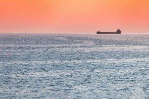 Little tugboat and big cargo ship. Beautiful sunset over sea. Breathtaking travel view, copy space. photo