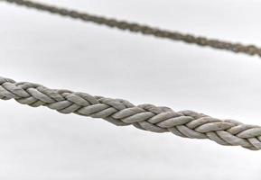 Two sail ropes hanging from fishing ship or yacht, close up photo