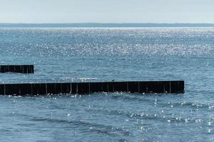 Breakwater on beach. Wooden sea separator. Beautiful seascape. Protection holidaymakers from effects of both weather and longshore drift. photo