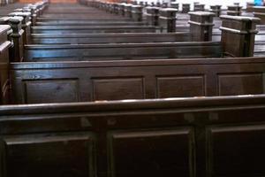 Cathedral benches. Rows of pews in christian church. Heavy solid uncomfortable wooden seats. photo
