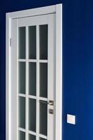 White interior door with handle. Blue wall in modern apartment photo