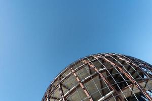 Unfinished sphere shape building, copy space. Construction of futuristic shopping mall or museum. Building constructed of concrete and reinforcement. photo