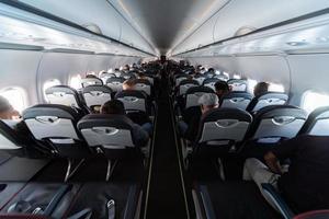 Airplane cabin seats with passengers. Economy class of new cheapest low-cost airlines without delay or cancellation of flight. Travel trip to another country. photo
