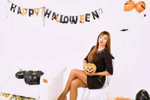 mujer joven con calabaza negra en la decoración de halloween foto