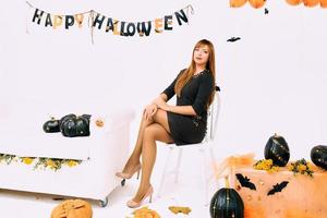 mujer joven con calabaza negra en la decoración de halloween foto