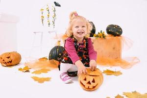 divertida y linda niña curva rubia con calabaza en decoración de halloween foto