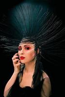 portrait of young beautiful woman like witch with red lips and black crown on dark background. Black dark beauty, Halloween concept photo