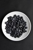 Black blueberries Vaccinium myrtillus on a white plate. photo