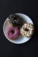 Delicious sweet donuts on a white plate. Donuts in glaze with filling close-up. photo