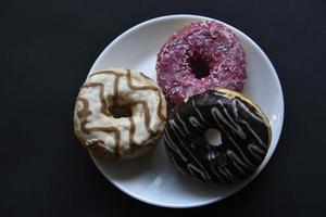 Delicious sweet donuts on a white plate. Donuts in glaze with filling close-up. photo