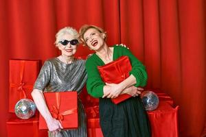 Stylish and fancy senior and mature woman at the party with gift boxes. Party, celebration, technology concept photo