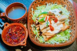 Mexican flautas with lettuce, avocado, cream, sauce and fresh water photo