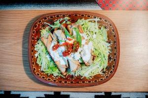 Mexican flautas with lettuce, avocado, cream, sauce and fresh water photo