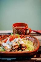 Mexican flautas with lettuce, avocado, cream, sauce and fresh water photo