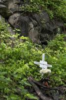 cross on the sidewalk of a deceased person huentitan canyon in guadalajara, mountains and trees, green vegetation and sky with clouds, mexico photo