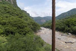 rusty cable, river and mountain in the background, vegetation barranca huentitan, guadalajara photo