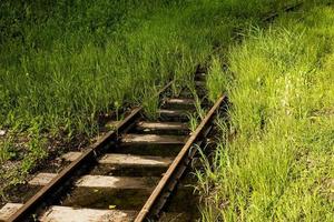 The railroad tracks are flooded with water and overgrown with grass. Abandoned railway track. photo