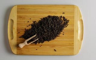 Dry black tea with bergamot flavor Gray graph as background, top view. A handful of tea on a wooden kitchen board. photo