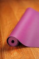 A lilac yoga mat is twisted on the wooden floor. photo