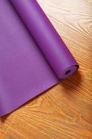 A lilac yoga mat is twisted on the wooden floor. photo