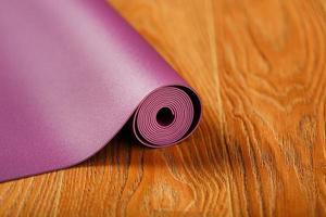 A lilac yoga mat is twisted on the wooden floor. photo