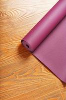 A lilac yoga mat is twisted on the wooden floor. photo