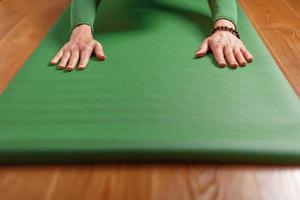 A woman does Yoga on a green rug at home in the living room. photo