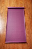 A lilac-colored yoga mat is spread out on the wooden floor with a Ganapati figurine photo