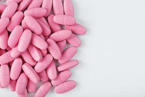 Pink vitamin pills for women on a white background. photo