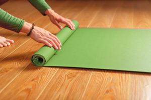 A woman collects a green mat after a yoga class photo