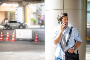 The business man talking with smart phone on their way. Feeling happy and relaxing, Casual young businessman wearing suit jacket and shoulder bag. photo