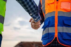 Close up of Engineers shaking hands at construction site, Construction worker in protective uniform shaking hands with foreman at construction site photo